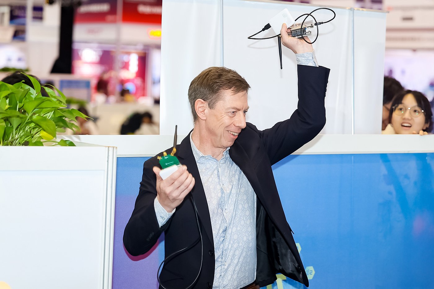 Blaise Paratte, Director of Technical Product Management at Semtech, conducting live stage demonstration of LR2021 technology, holding connected electronic devices with cables during hands-on product showcase